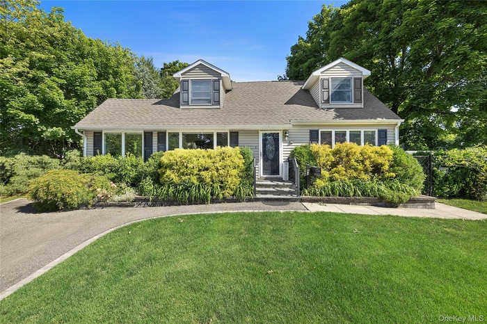 Traditional home exterior featuring light-colored siding, a dark roof, and two dormer windows