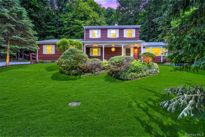 Colonial style residence featuring a barn red cedar shake siding exterior with white window trim and shutters