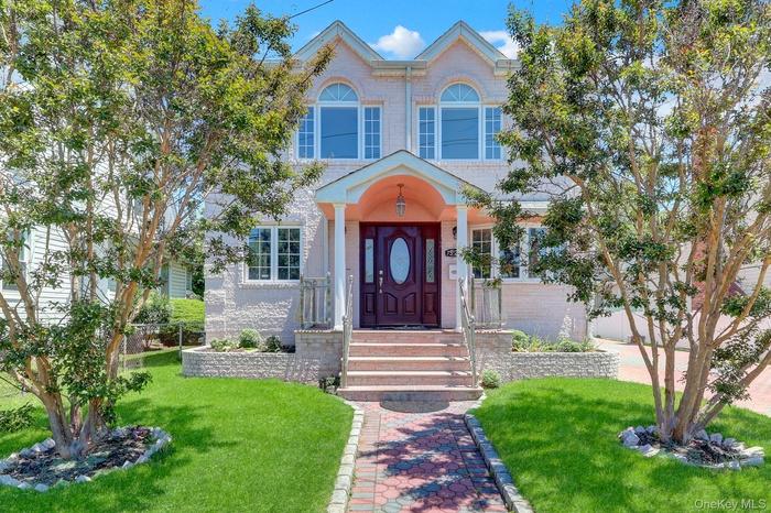 Residence featuring a textured light-colored facade, an arched entry portico, and a dark wood-finish front door with an oval glass insert