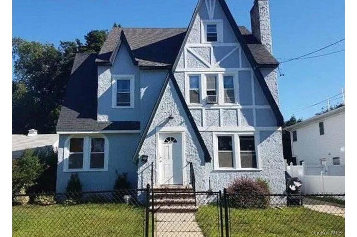 Distinctive Tudor Revival-style residence featuring a prominent front-facing gable and textured stucco siding