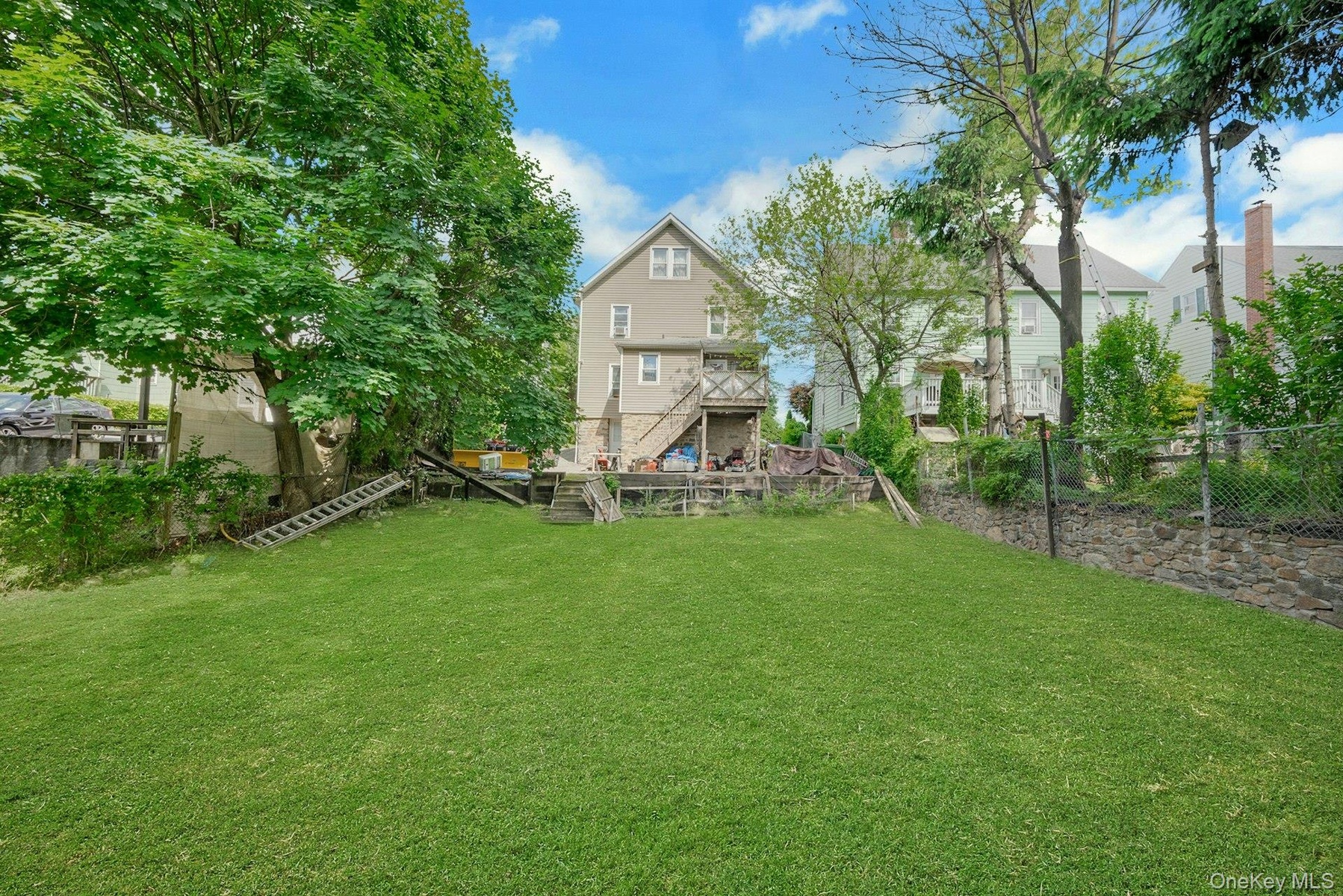 Large back yard with stonewall and fencing