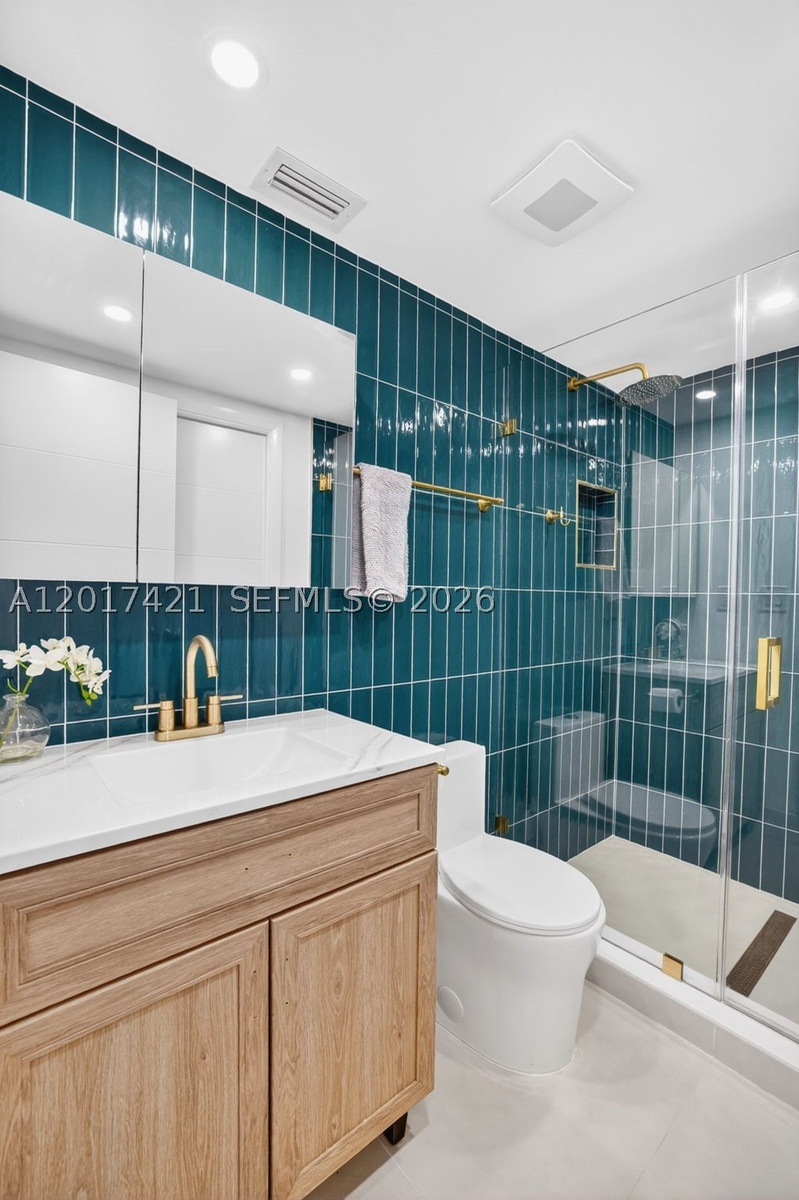 Upstairs guest bathroom (also en suite for one bedroom). Beautiful wall tile and vanity / medicine cabinet. Frameless shower enclosure