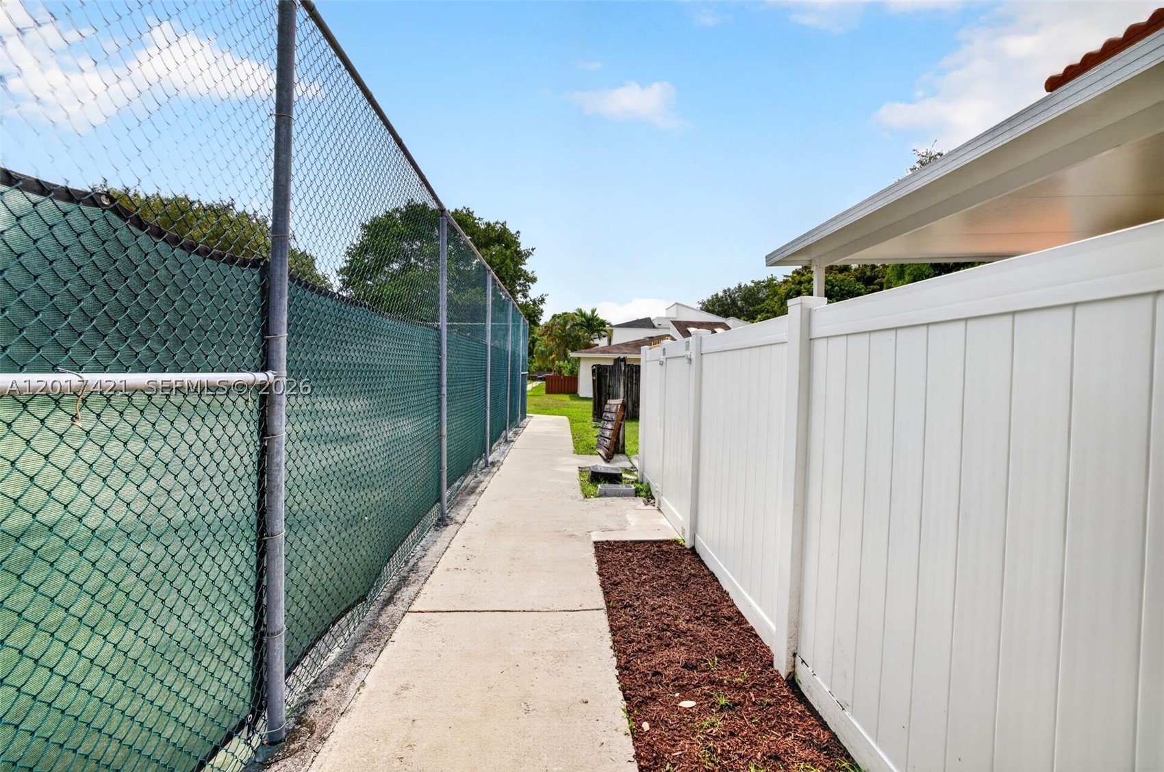 Sidewalk between tennis and backyard fence