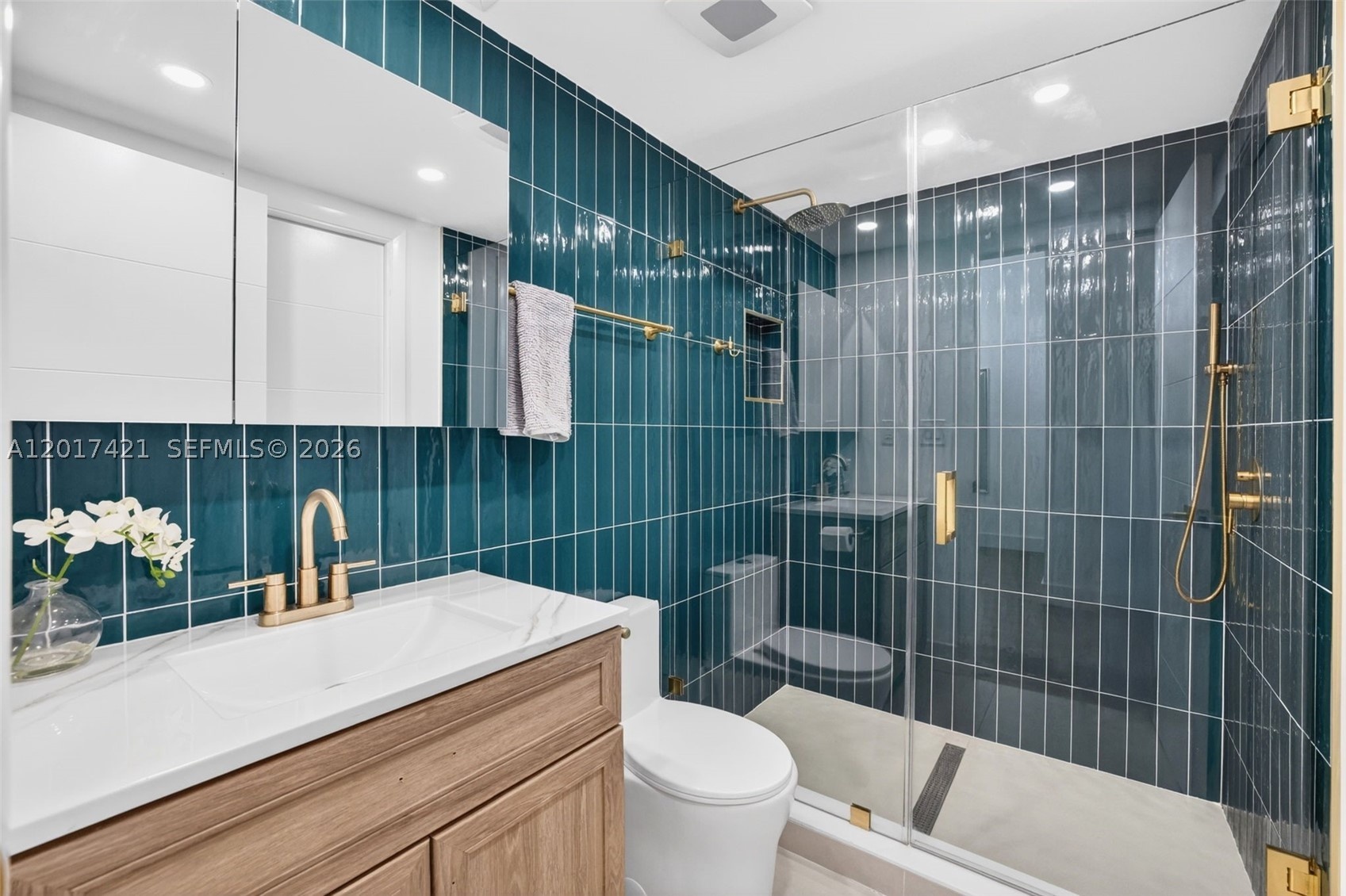 Upgraded bathroom w/ gorgeous finishes, rain shower head & handheld, tile to the ceiling, frameless shower door & medicine cabinet