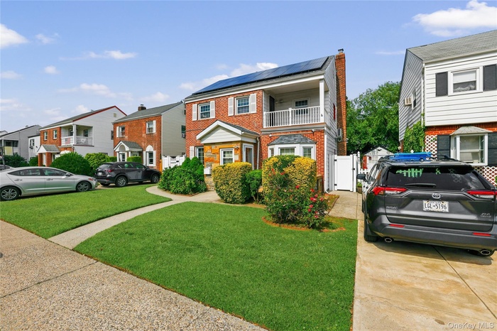 Brick exterior residence featuring a front lawn and paved driveway