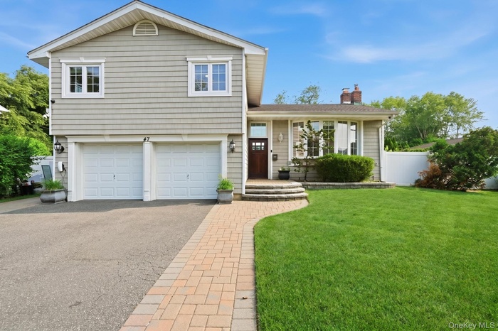 Split-level residence featuring light-colored siding and white trim
