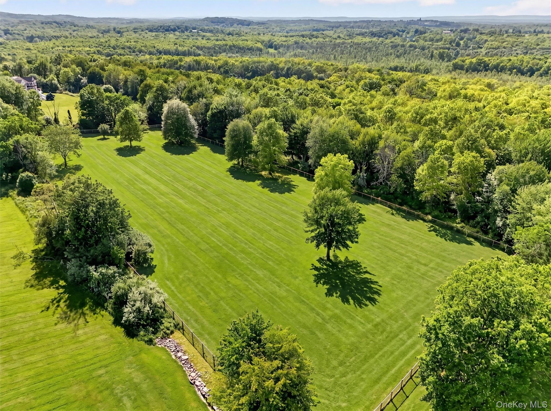 Beyond this large, fenced field is the wooded part of the property for trail riding, hiking, or additional fields or infrastructure