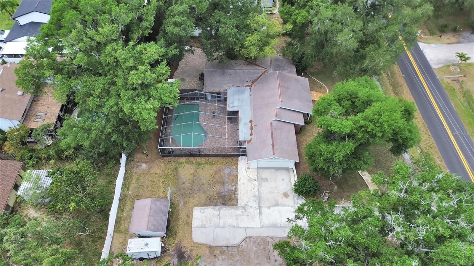 shows inground  pool with large screen enclosure, detached concrete block shed, lots of room for parking