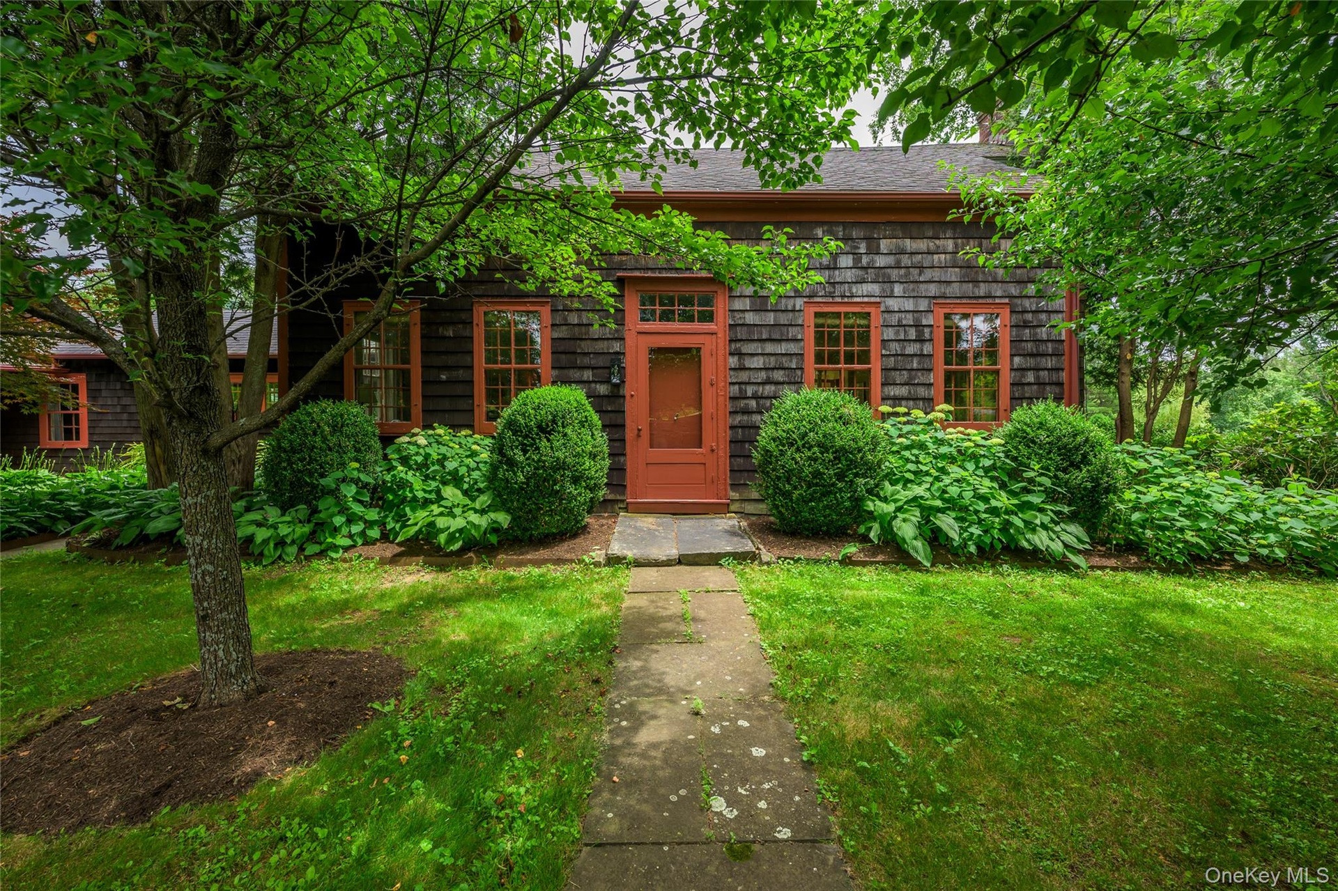 View of front of property featuring a shingled roof and a front yard