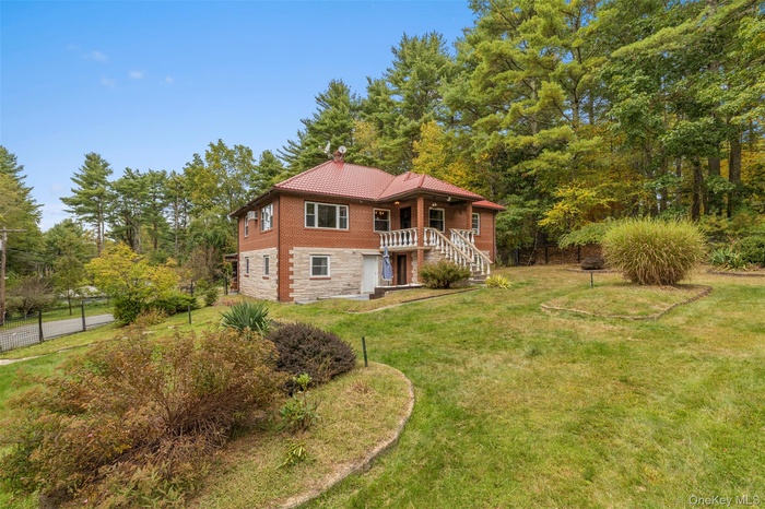 View of front of property featuring a chimney, stone siding, and view of scattered trees