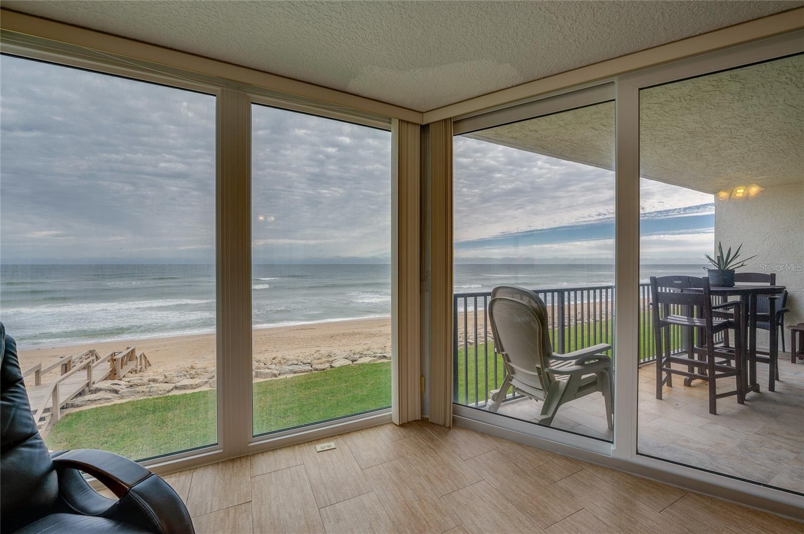 Expansive glass doors open directly to the covered balcony, creating seamless indoor-outdoor flow and capturing stunning views of the sand and surf.