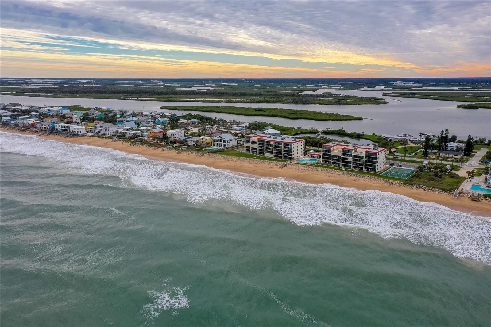 A reverse angle captures the southern horizon, dotted with colorful homes and calm estuary waters, emphasizing the secluded charm of this community.