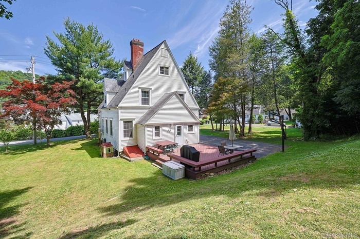 White-sided residence featuring a red brick chimney and a multi-level wood deck