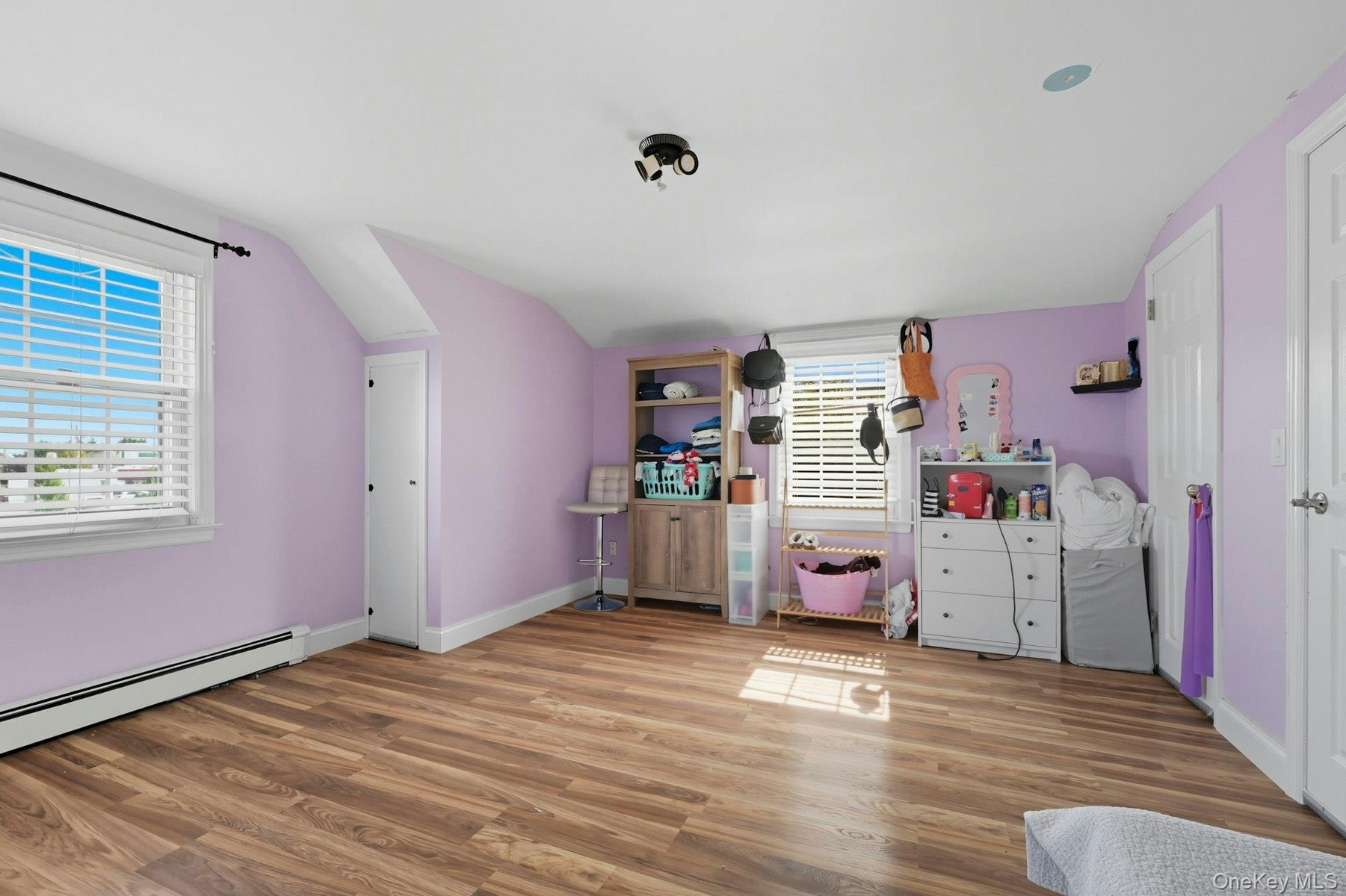 Bedroom featuring radiator, wood finished floors, vaulted ceiling
