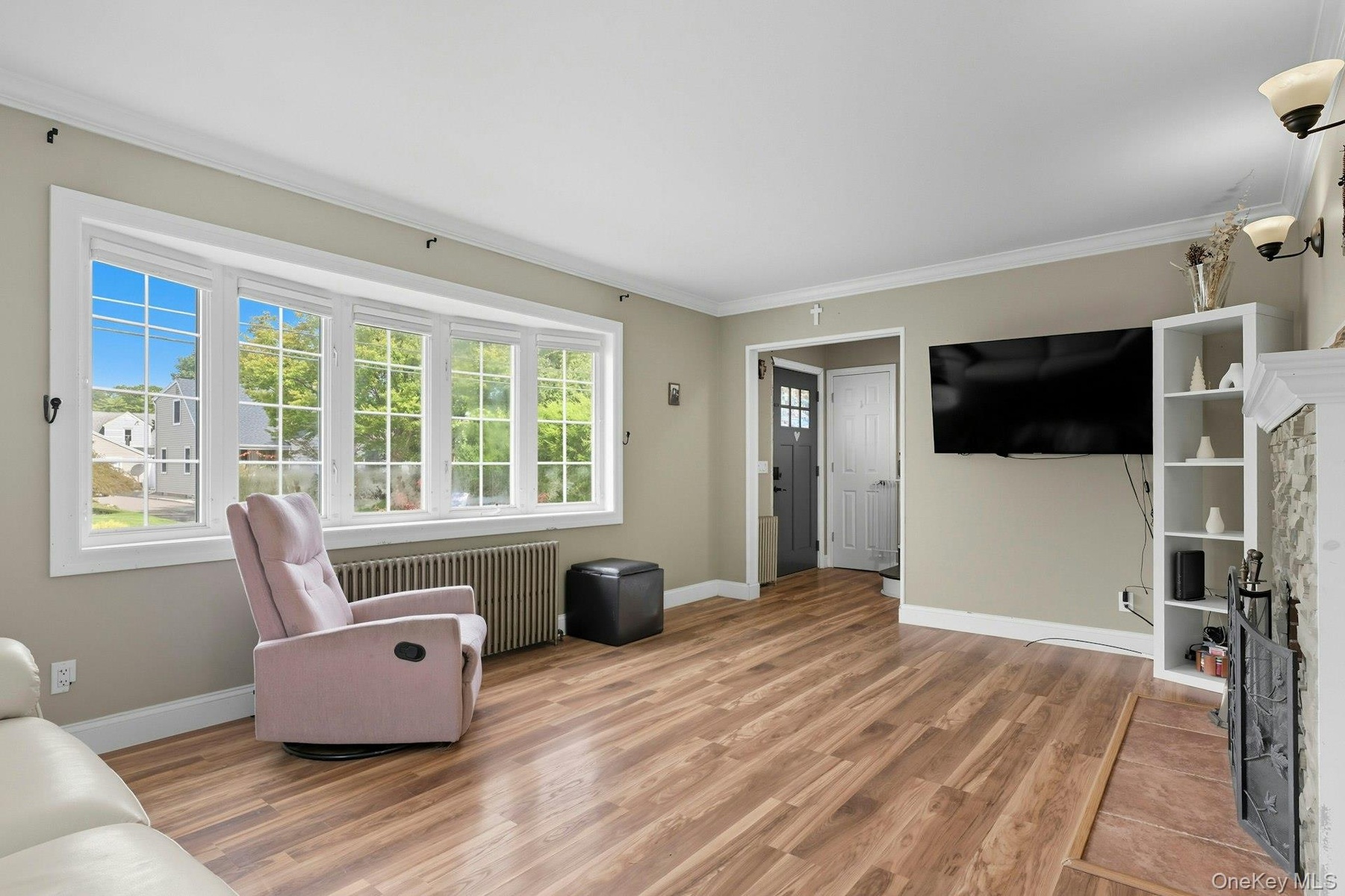 Living room featuring ornamental molding, radiator heating unit, light wood-type flooring, and a fireplace