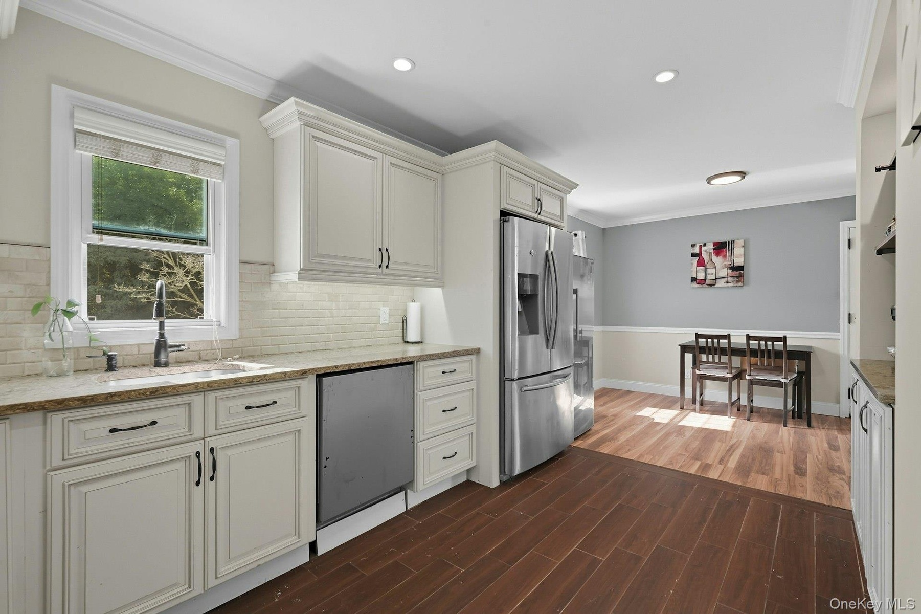 Kitchen featuring crown molding, dark wood-type flooring, stainless steel refrigerator with ice dispenser, light stone countertops