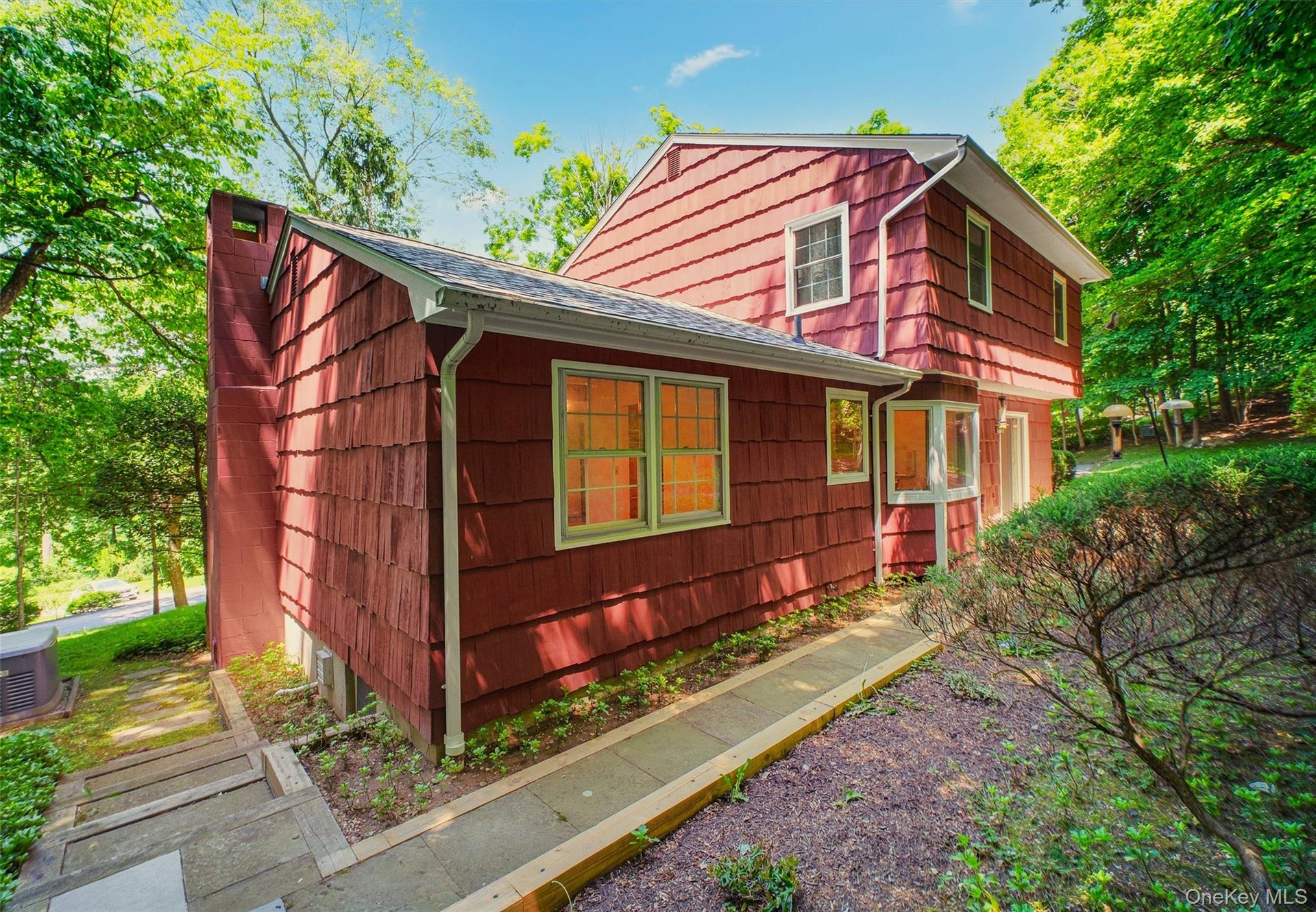 Red cedar shake siding with white trim w/blue stone walkway leading from rear patio to side yard