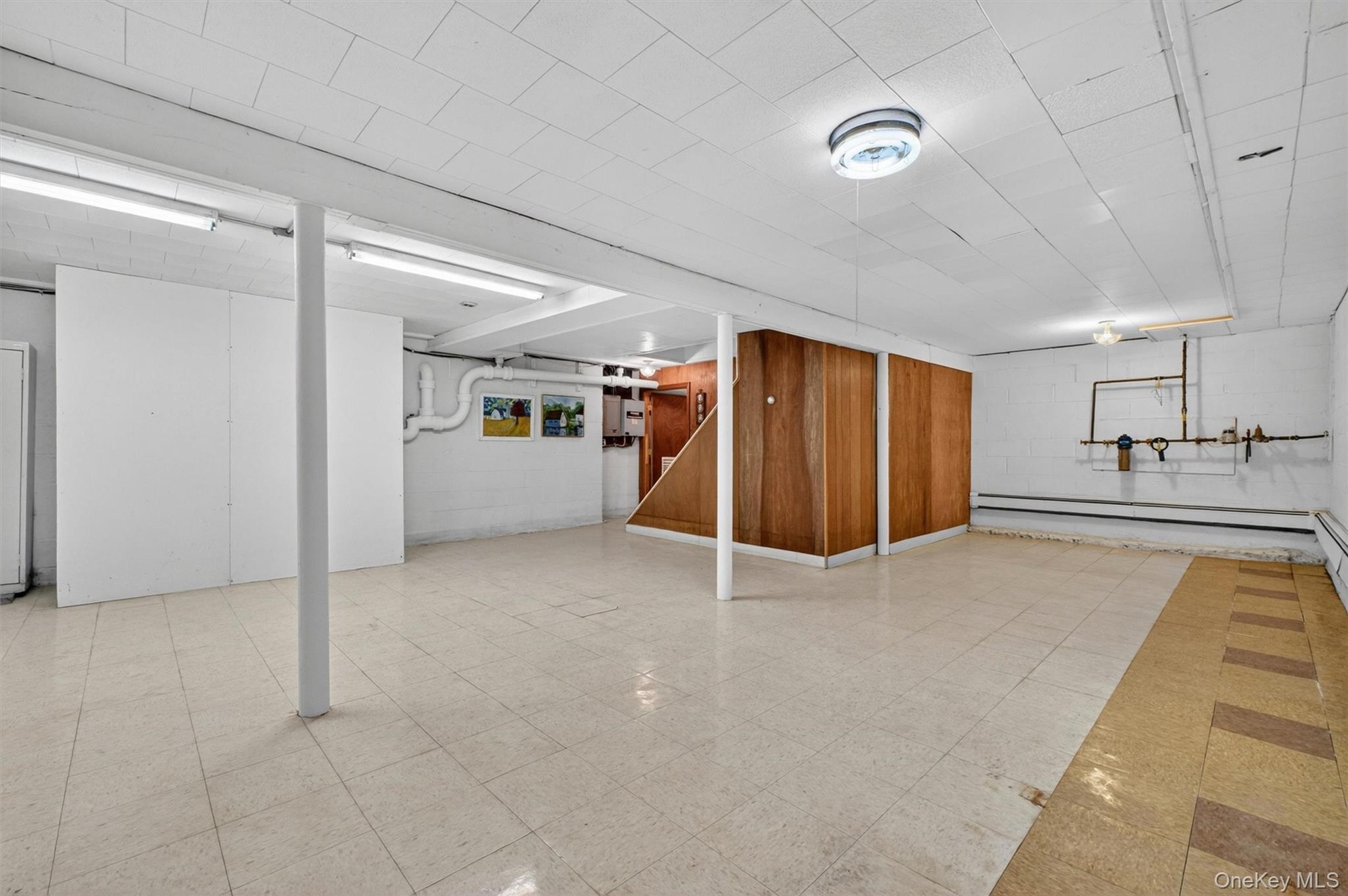 Versatile finished basement featuring a drop ceiling, exposed support beams, & tiled    flooring, & electric heat.