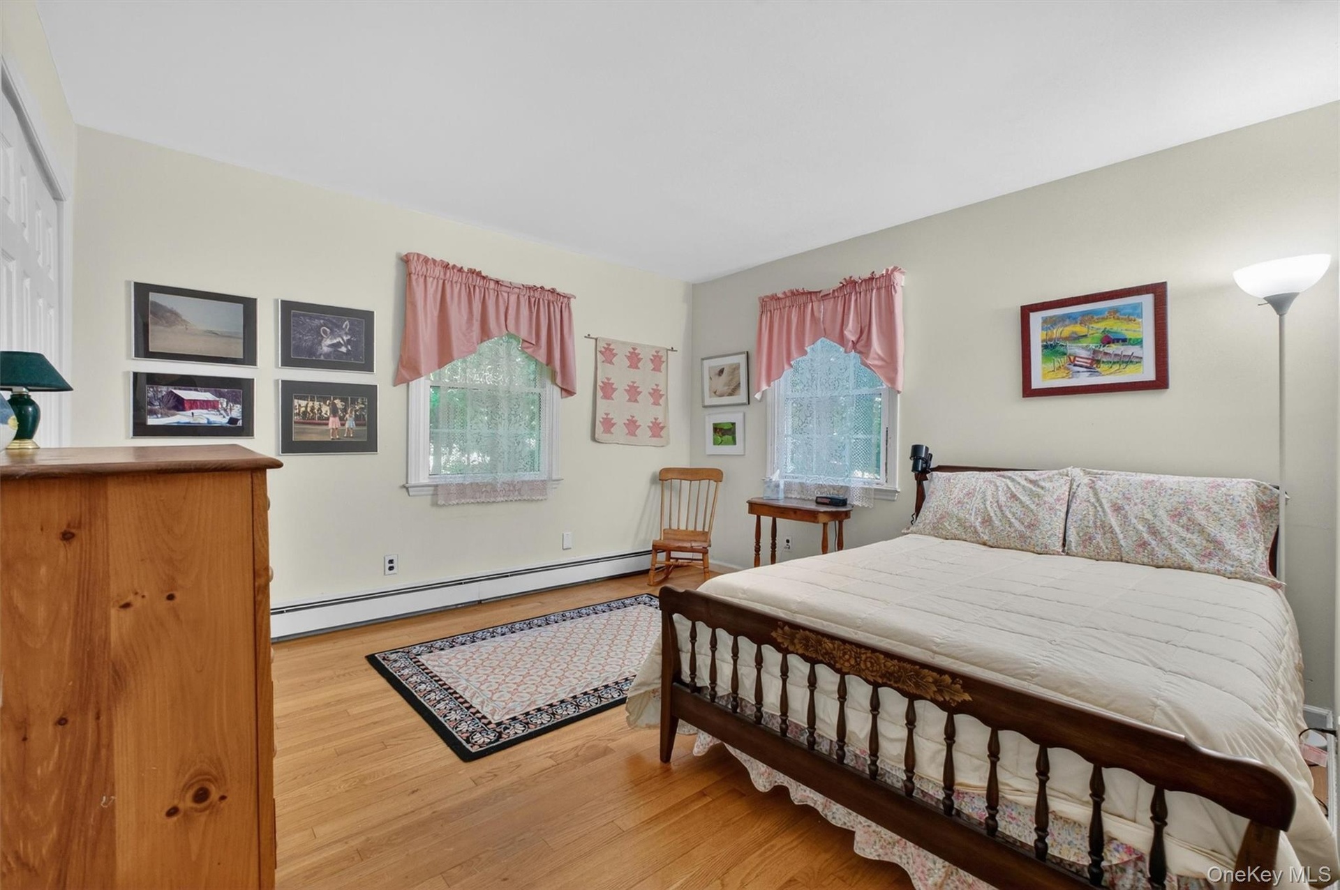 Bedroom #3 w/wood-finish flooring, two windows, and light-toned wall paint