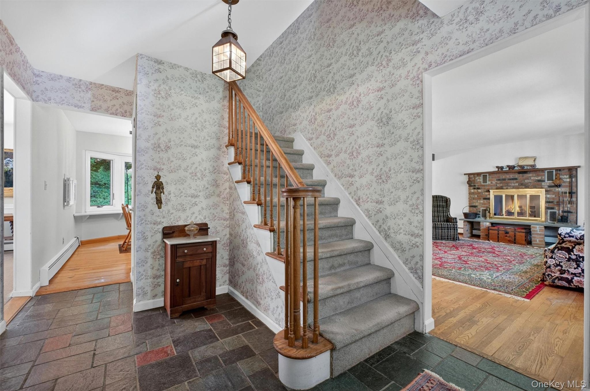 Foyer with natural stone tile flooring and a carpeted staircase featuring a wood banister