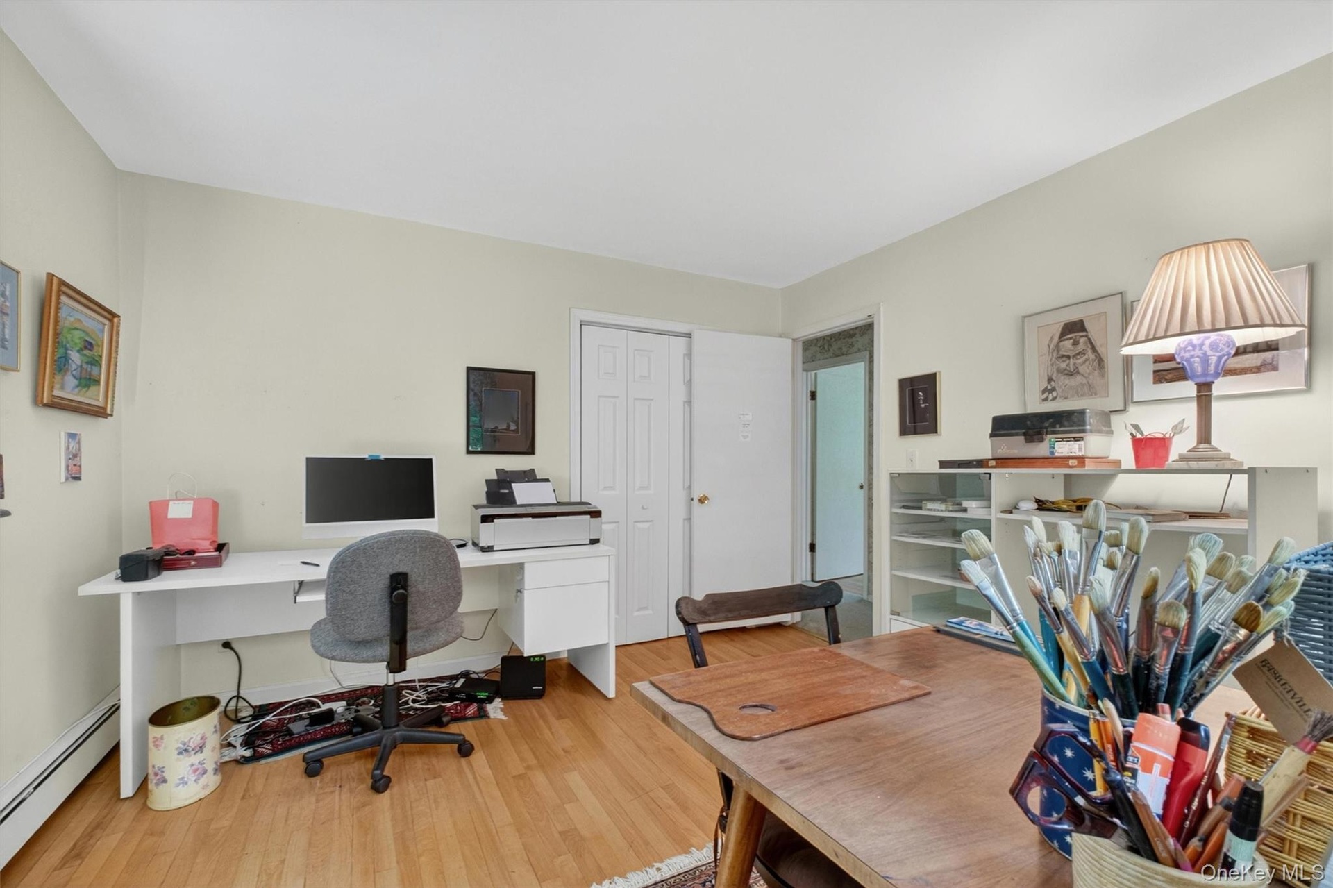Bedroom #2 (used as office) w/light-toned walls, wood-finish flooring, two double-hung windows, and white trim baseboards