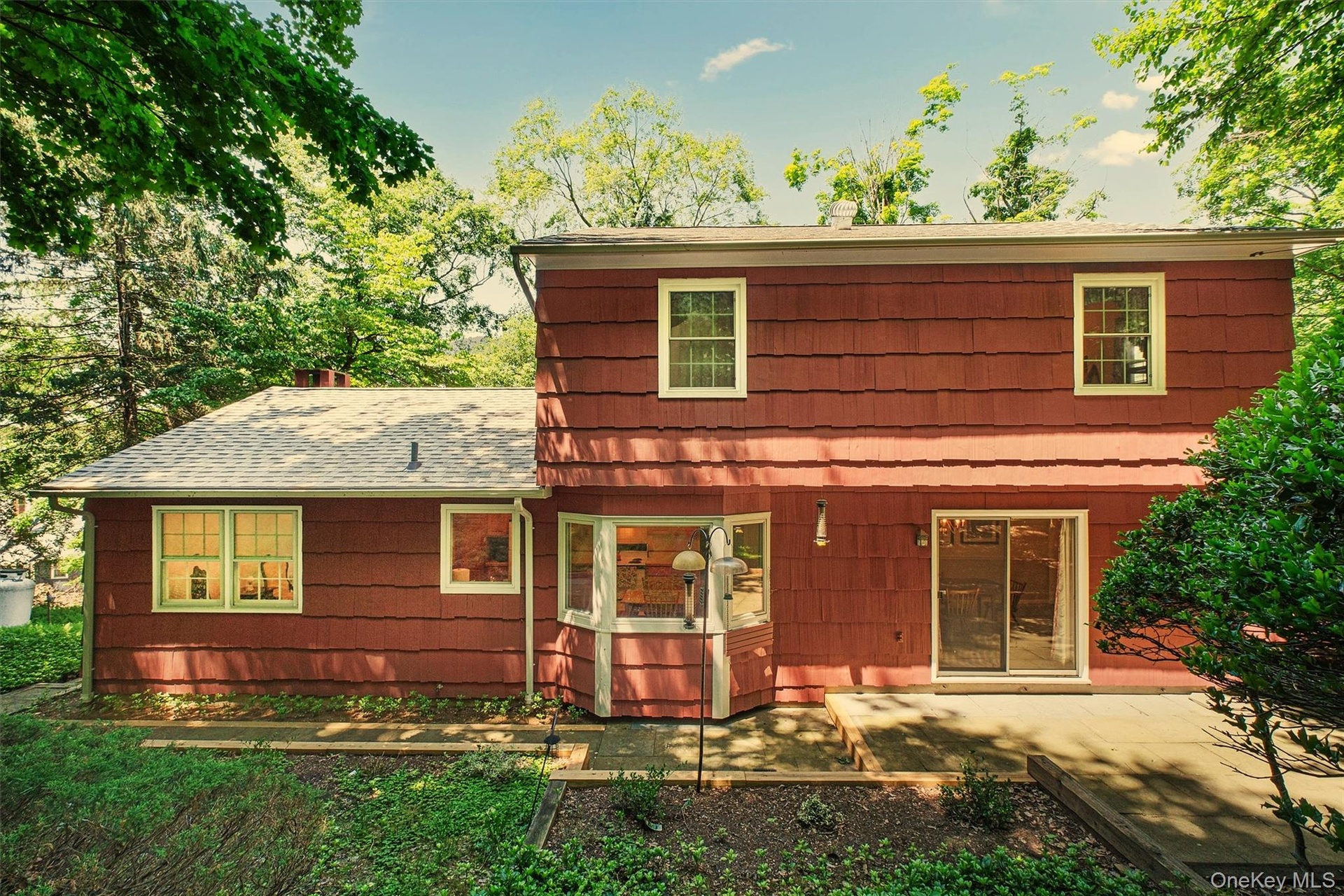 Rear view of house, patio, sliding glass doors from formal dining room with a multi-level roofline
