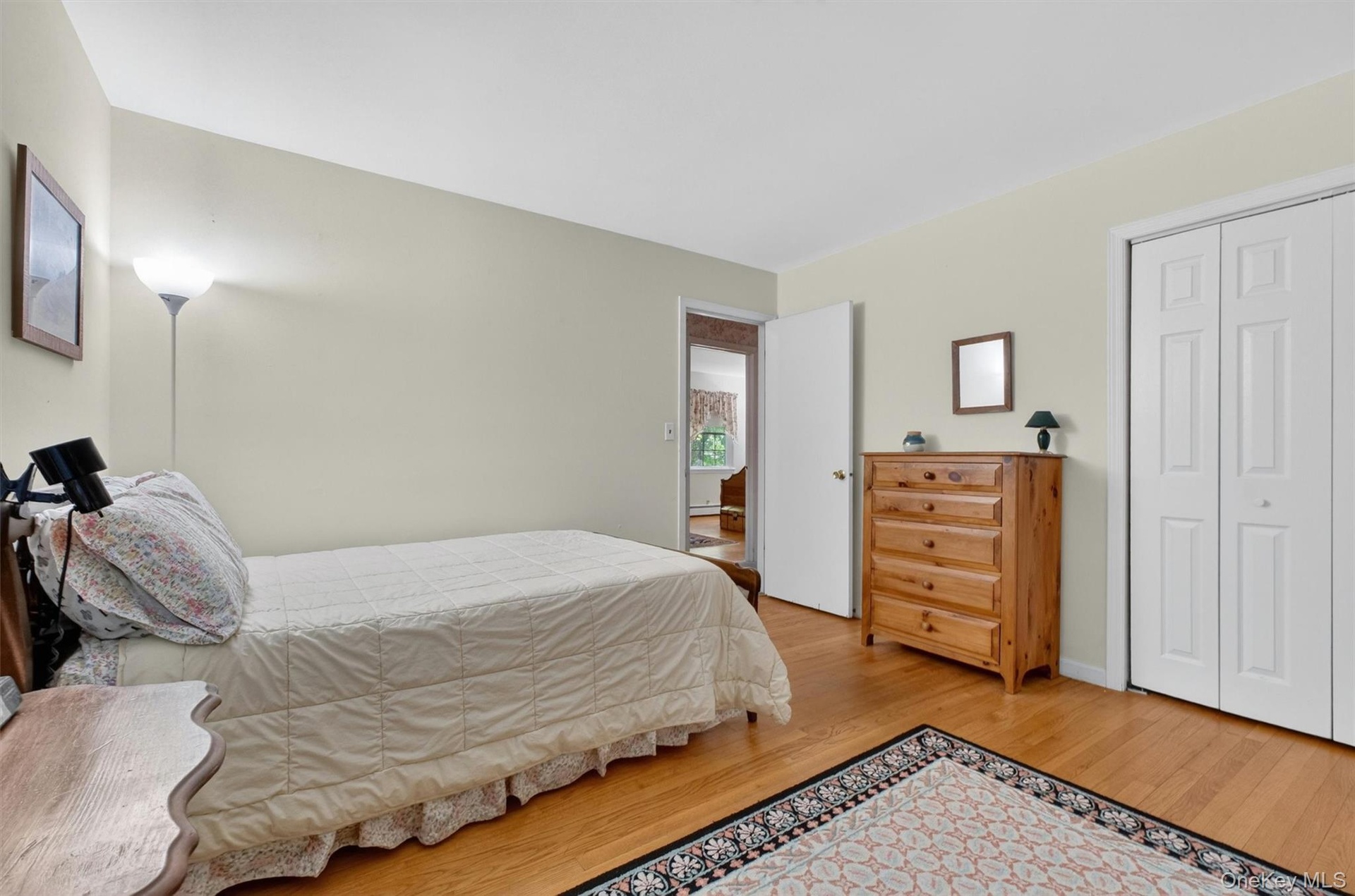 Bedroom #3 featuring wood-finish flooring, light-colored walls, a white ceiling, and a paneled bifold closet door
