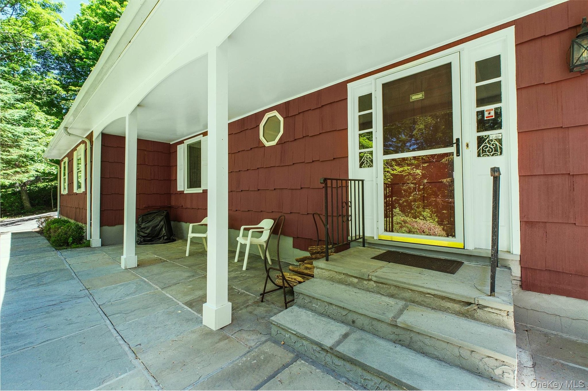 Covered front porch featuring a stone patio and steps to front door