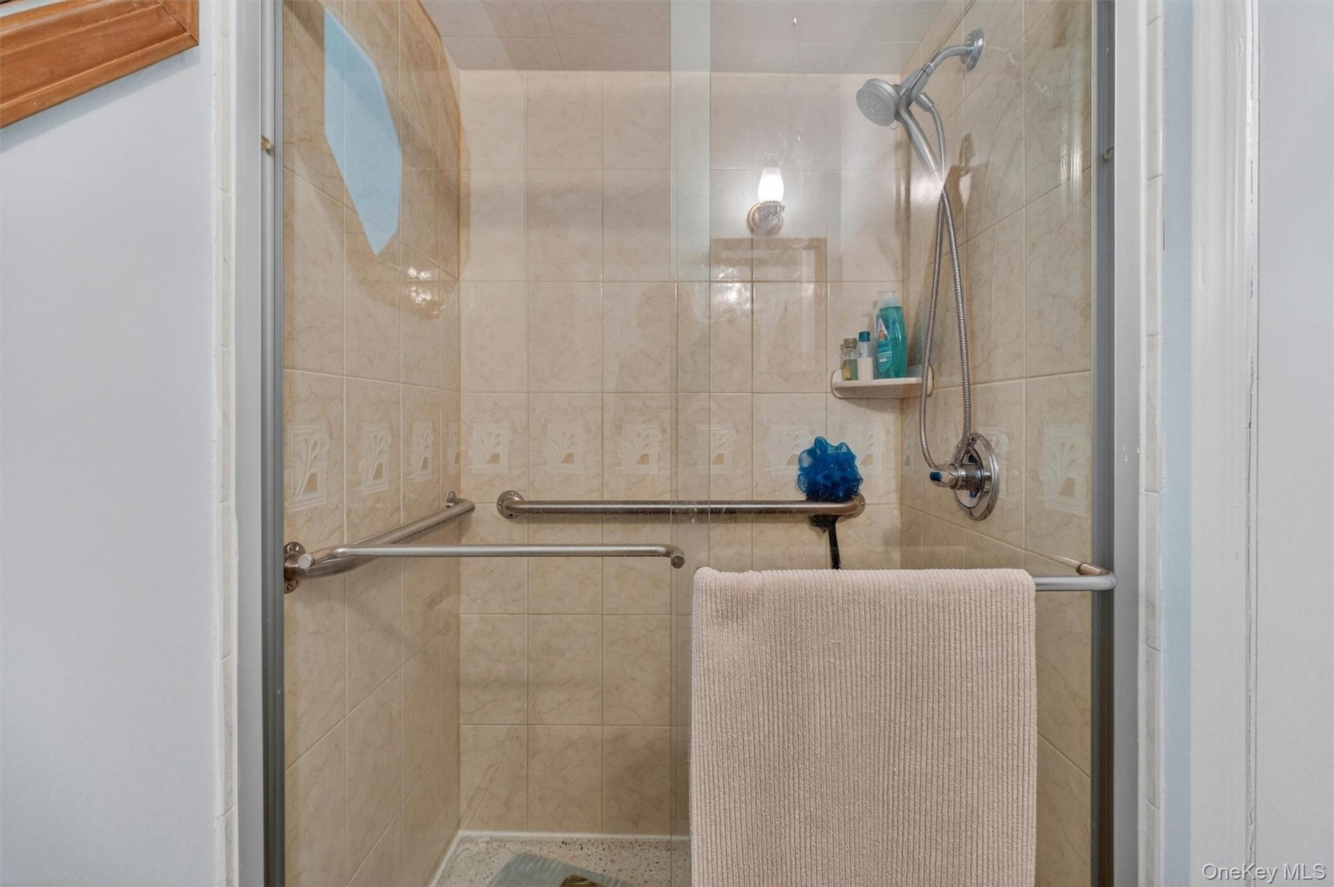 1st Fl. Full Bath w/Tiled shower enclosure featuring a clear glass door, chrome fixtures, and integrated grab bars