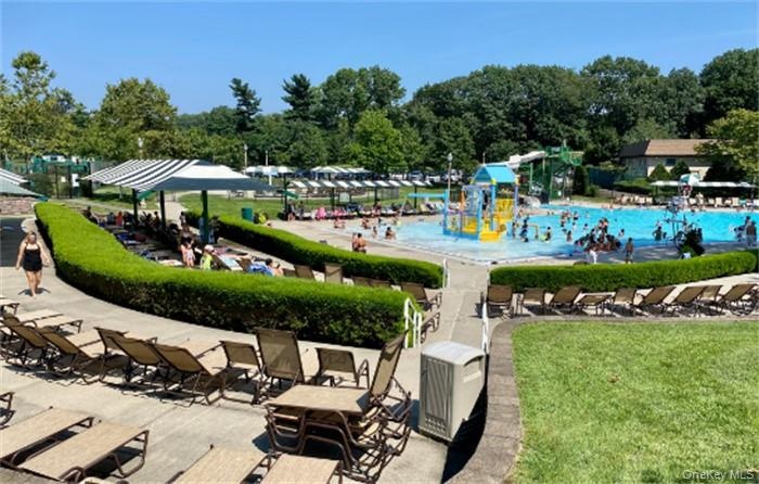 Community aquatic area featuring a large swimming pool, a separate shallow play pool with water features, and surrounding concrete lounge decks