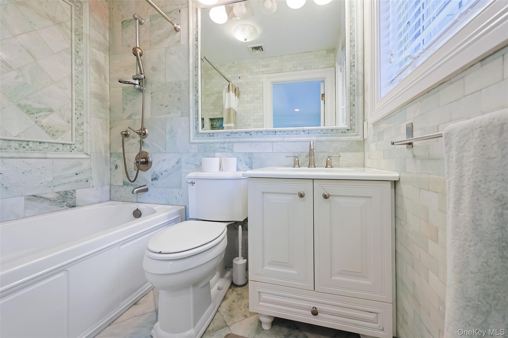 Bathroom featuring a white vanity with a single basin, a chrome faucet, and a large wall mirror with integrated lighting