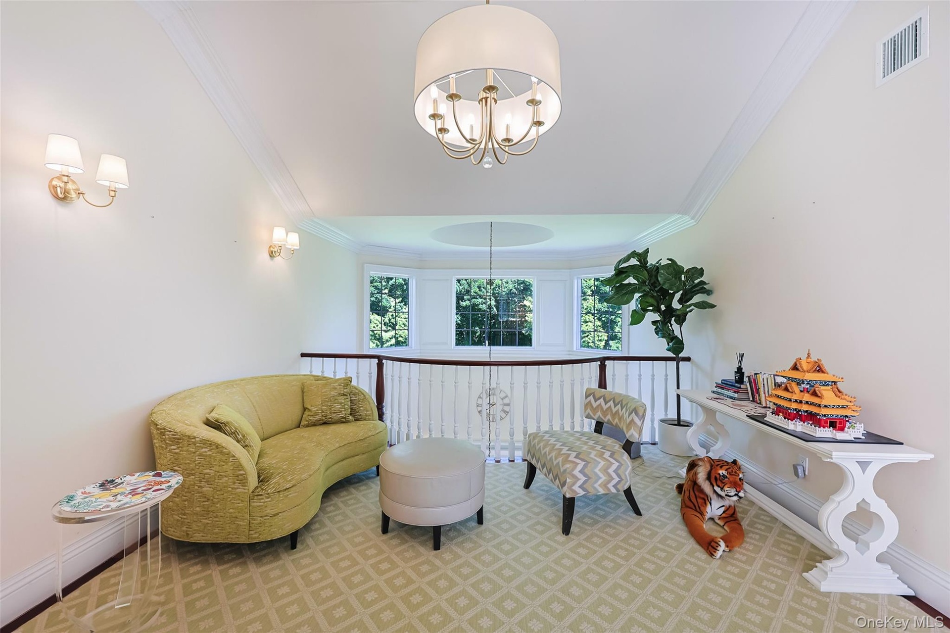 Bright upper-level landing featuring a large bay window, crown molding, and a drum-shade chandelier