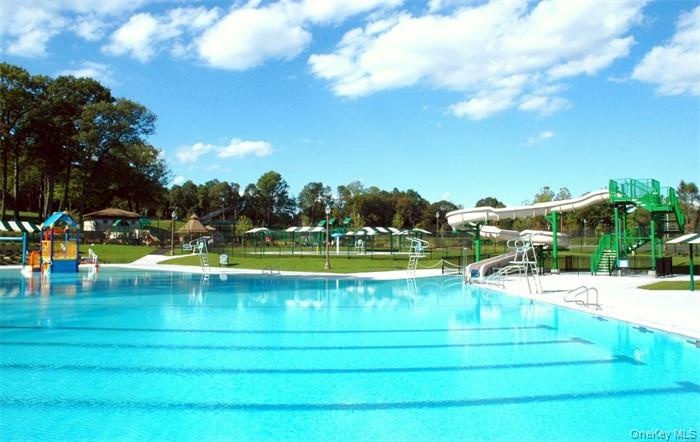 Expansive aquatic facility featuring a large swimming pool, an additional children's water play structure, and multiple water slides