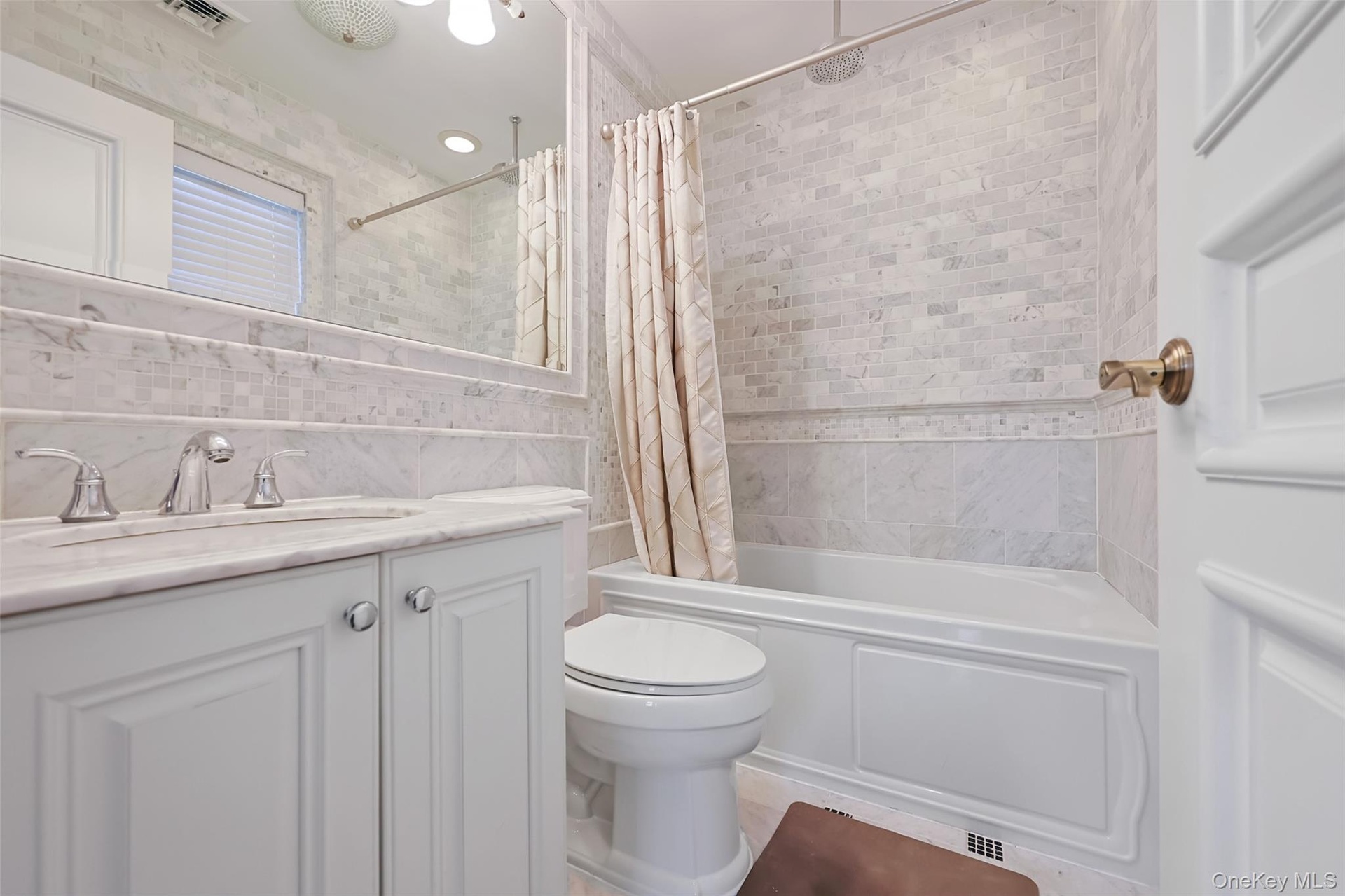 Bathroom featuring a white vanity with a marble countertop, undermount sink, and chrome faucet