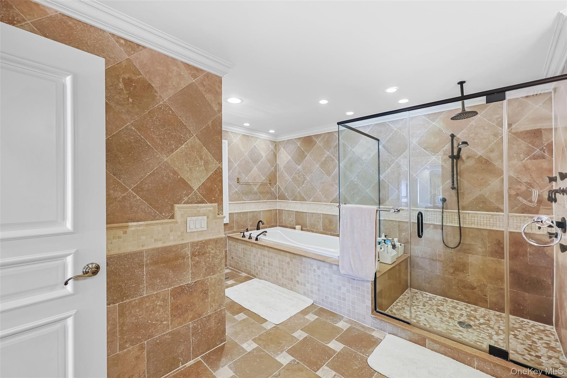 Spacious bathroom featuring diagonal-set floor and wall tiling, a built-in soaking tub, and a separate glass-enclosed shower with multiple showerheads