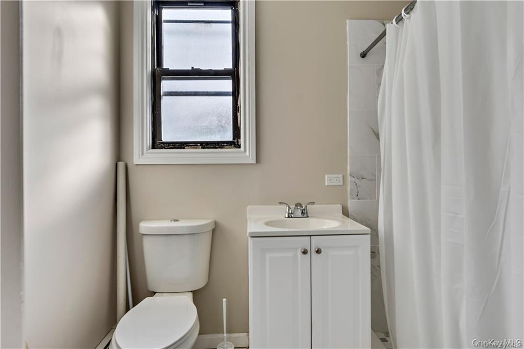 Bathroom featuring a white vanity with a ceramic sink, a chrome faucet, and a two-door cabinet