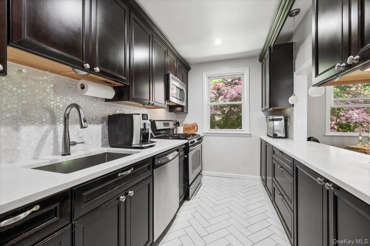 Renovated kitchen with stainless steel appliances, tons of cabinets, attractive tile backsplash and white quartzite countertops.