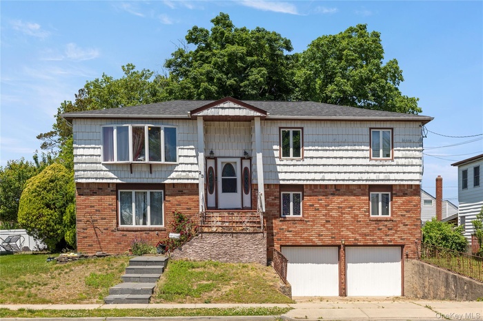 Three-story residence featuring a brick and white shingle facade