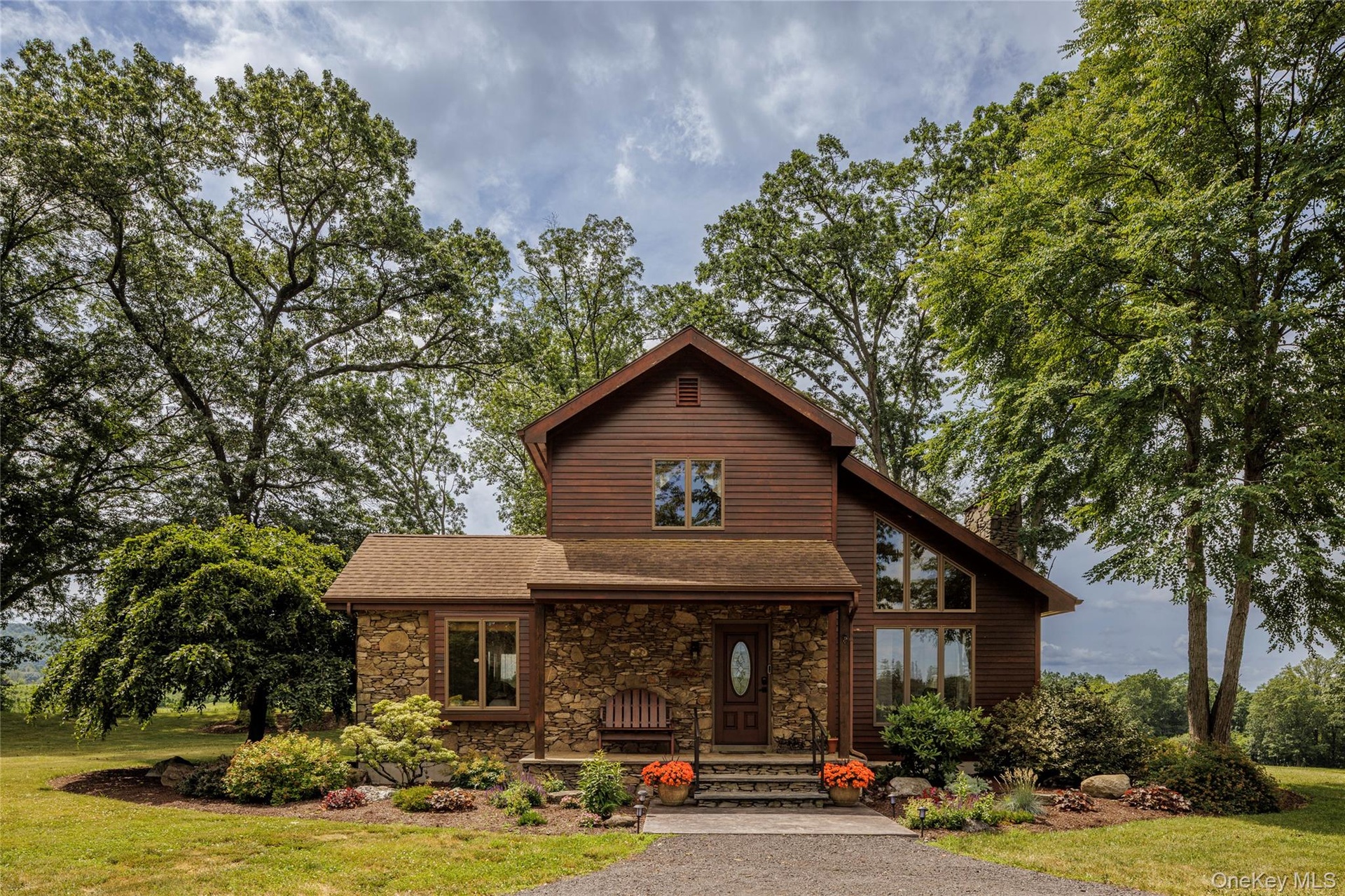 Rustic home featuring stone siding, a front lawn, and a shingled roof