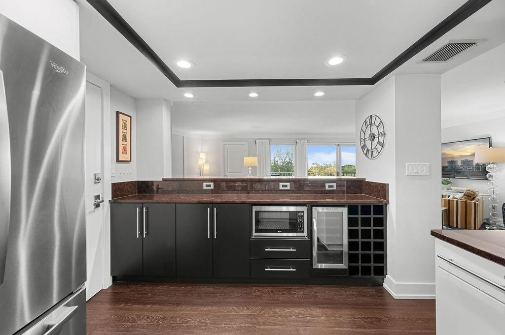 Custom bar area provides ample storage, a wine refridgerator, extra bottle storage and microwave.