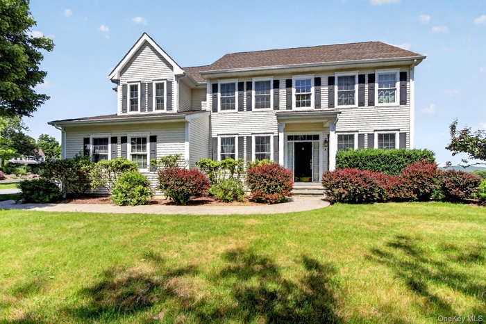 Traditional-style residence featuring light-colored siding and a dark roof