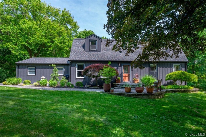 Classic Dutch Colonial -- dark-toned exterior with white trim windows.