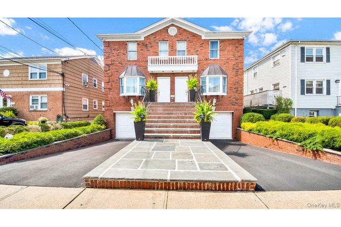 Brick Multi Family home featuring a symmetrical design, dual entry doors, and a stone-paved walkway