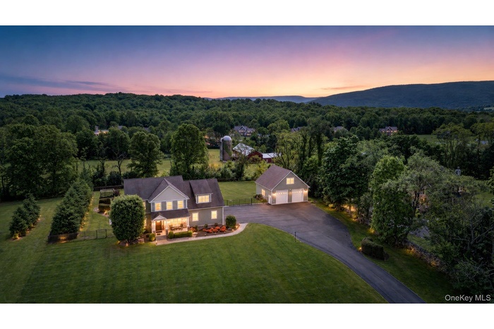 Spacious property featuring a two-story residence with a detached three-car garage, extensive paved driveway, and mature landscaping