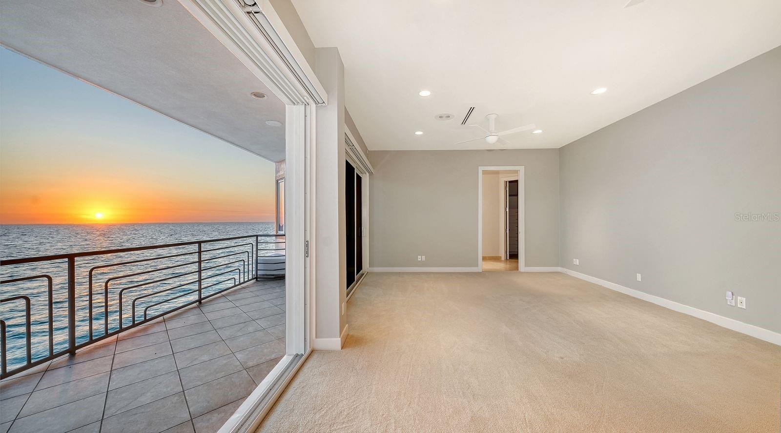 Primary bedroom with sliders to balcony with stunning sunsets