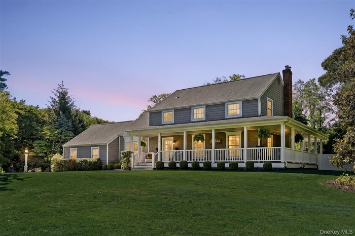 Cape Cod style residence featuring gray siding and a prominent chimney