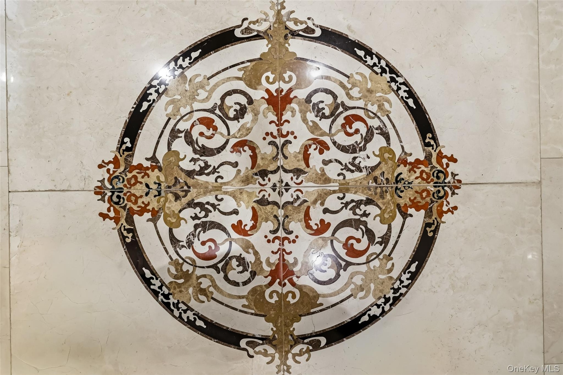 Decorative floor medallion featuring intricate scrollwork and a multi-tone palette, set into light-toned tile flooring