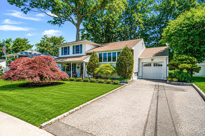 Manicured front lawn with mature plantings, garage