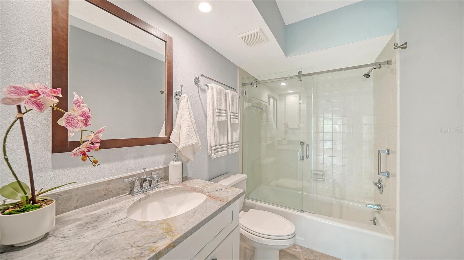 Guest bathroom with granite countertop and glassed shower/tub combination.