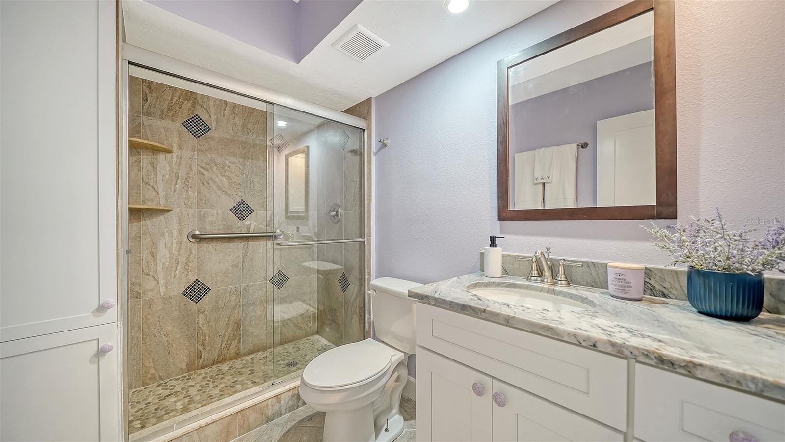 Primary bathroom with granite counters & glassed walk-in shower.